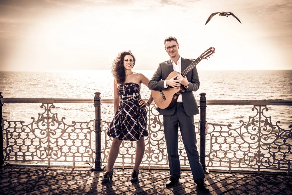 Lizzy and Duncan with an acoustic guitar on Brighton seafront